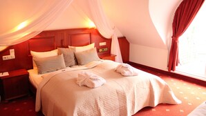 Een slaapkamer met hemelbed, nachtkastje en raam met gordijnen.