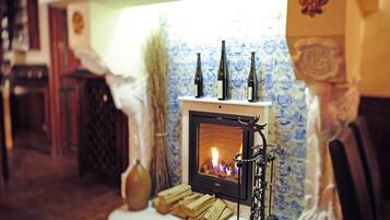 A cozy room with a fireplace, a tiled wall, and a wooden table with bottles and logs.