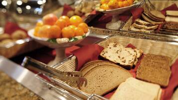 A buffet with various food items including bread, oranges, and other fruits.