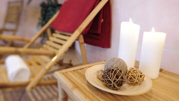 Une chaise en bois, une serviette rouge, deux bougies blanches et des boules décoratives sont posés sur une table.