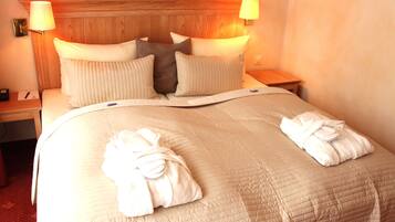 Een hotelkamer met een groot bed, twee bedlampen en twee handdoeken op het bed.