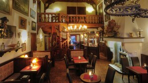 Een restaurant met houten inrichting, meerdere eetgedeeltes en een trap naar een bovenverdieping.