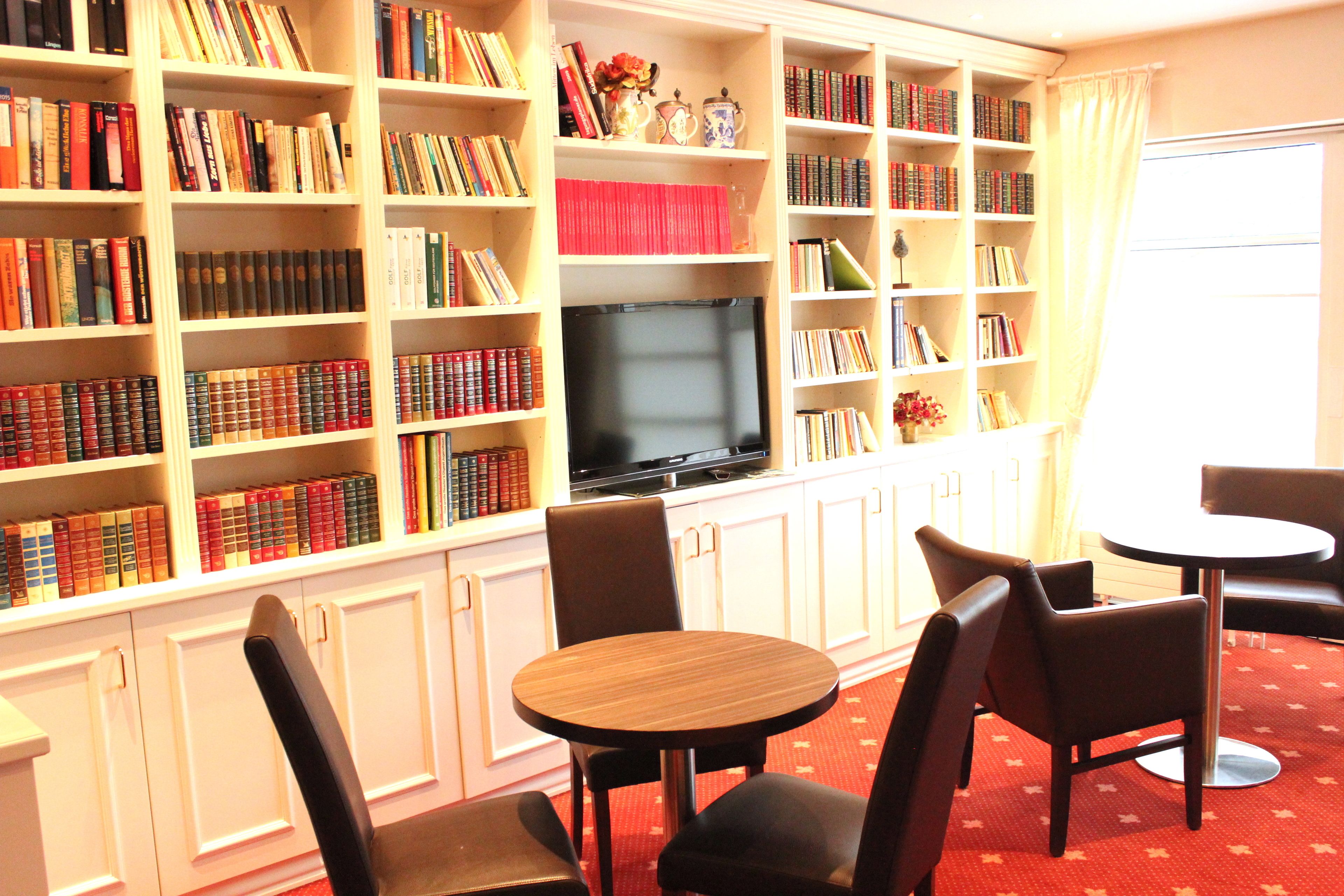 Una biblioteca con estanterías, televisión y zonas de descanso.
