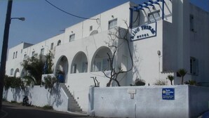 A white building with arched windows and a sign that reads "King Thyrs Hotel." - King Thiras (Santorini)