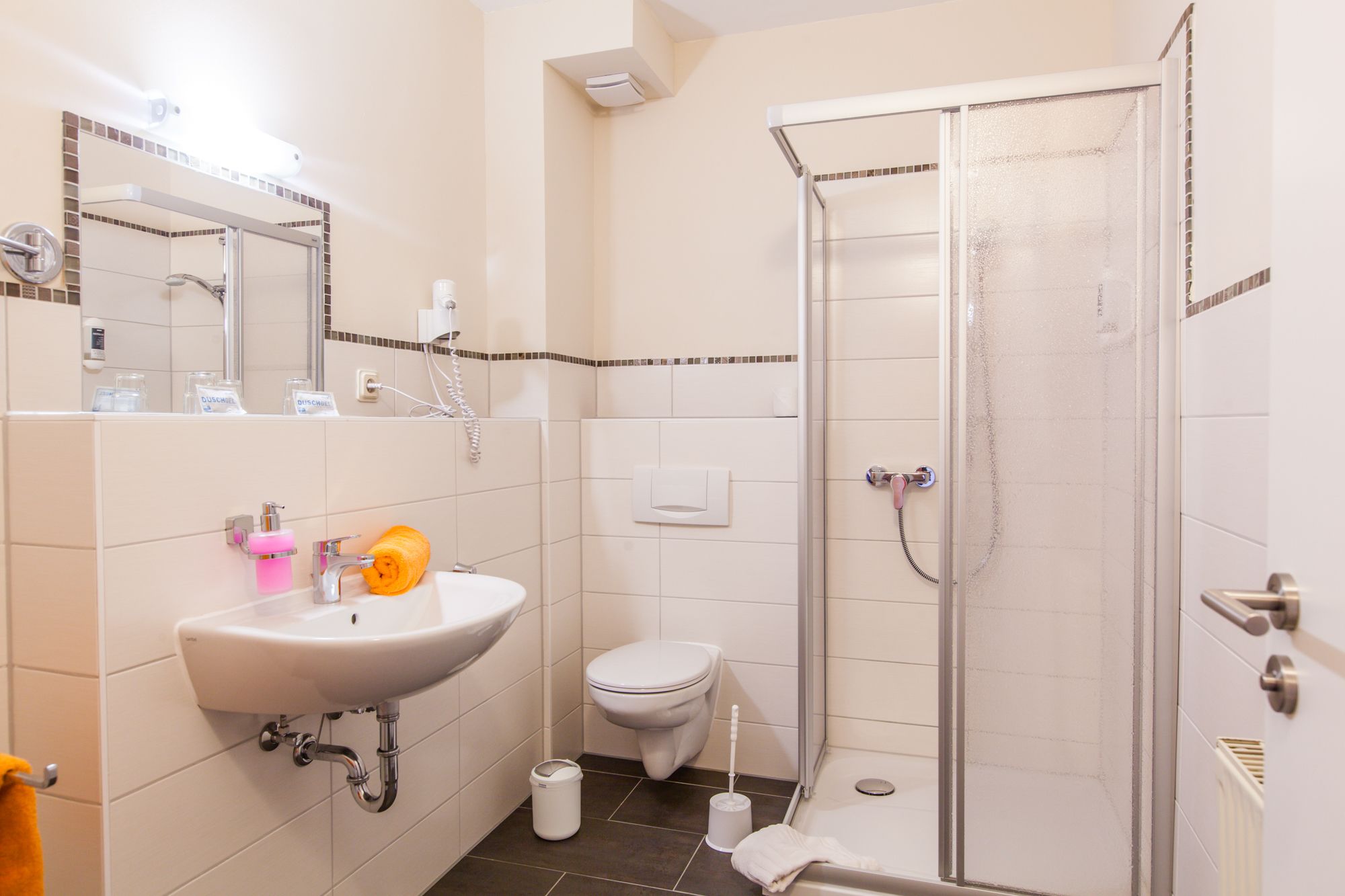 Ein Badezimmer mit einem weißen Waschbecken, einer Toilette und einer Duschkabine.