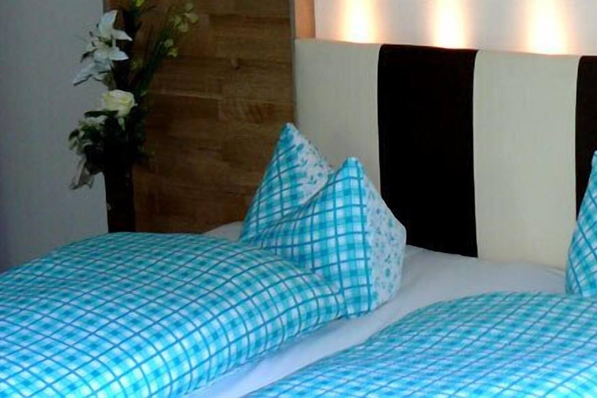 Una cama doble con ropa de cama a cuadros, un teléfono junto a la cama y un cabecero de madera.