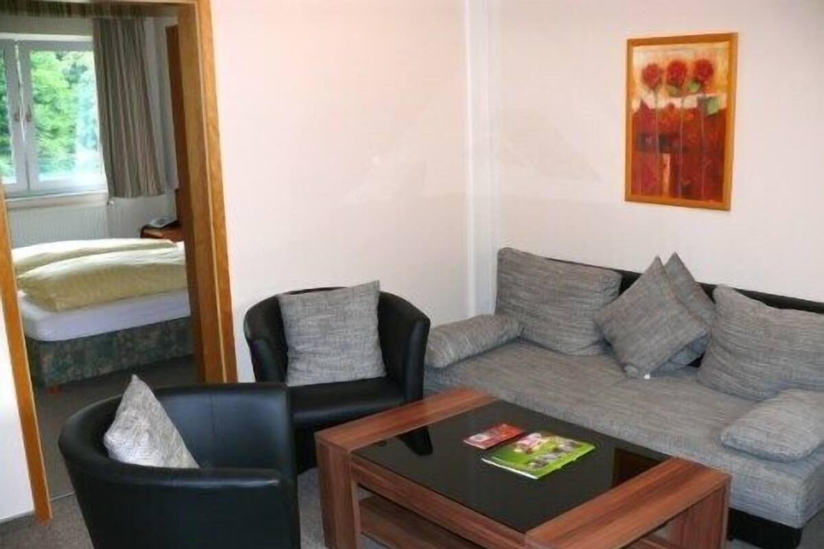 Una sala de estar con un sofá, dos sillones, una mesa de centro y un cuadro en la pared.