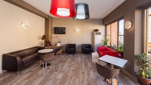 A modern interior with a sofa, chairs, a round table, and pendant lights. - Hotel Sorriso (Brenzone sul Garda)