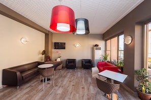 Ein modernes Interieur mit einer Couch, Sesseln, einem runden Tisch und Pendelleuchten.