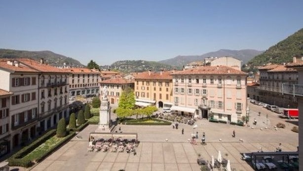 A square with historic buildings, a central monument, and a clear sky. - Albergo Firenze (Como)