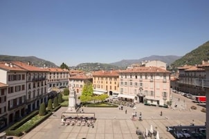 Una plaza con edificios históricos, un monumento central y cielo despejado.