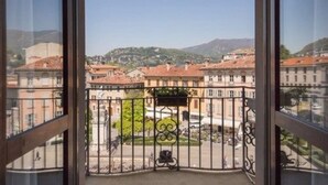A balcony with a wrought iron railing, a view of a town with buildings and a hill in the background. - Albergo Firenze (Como)