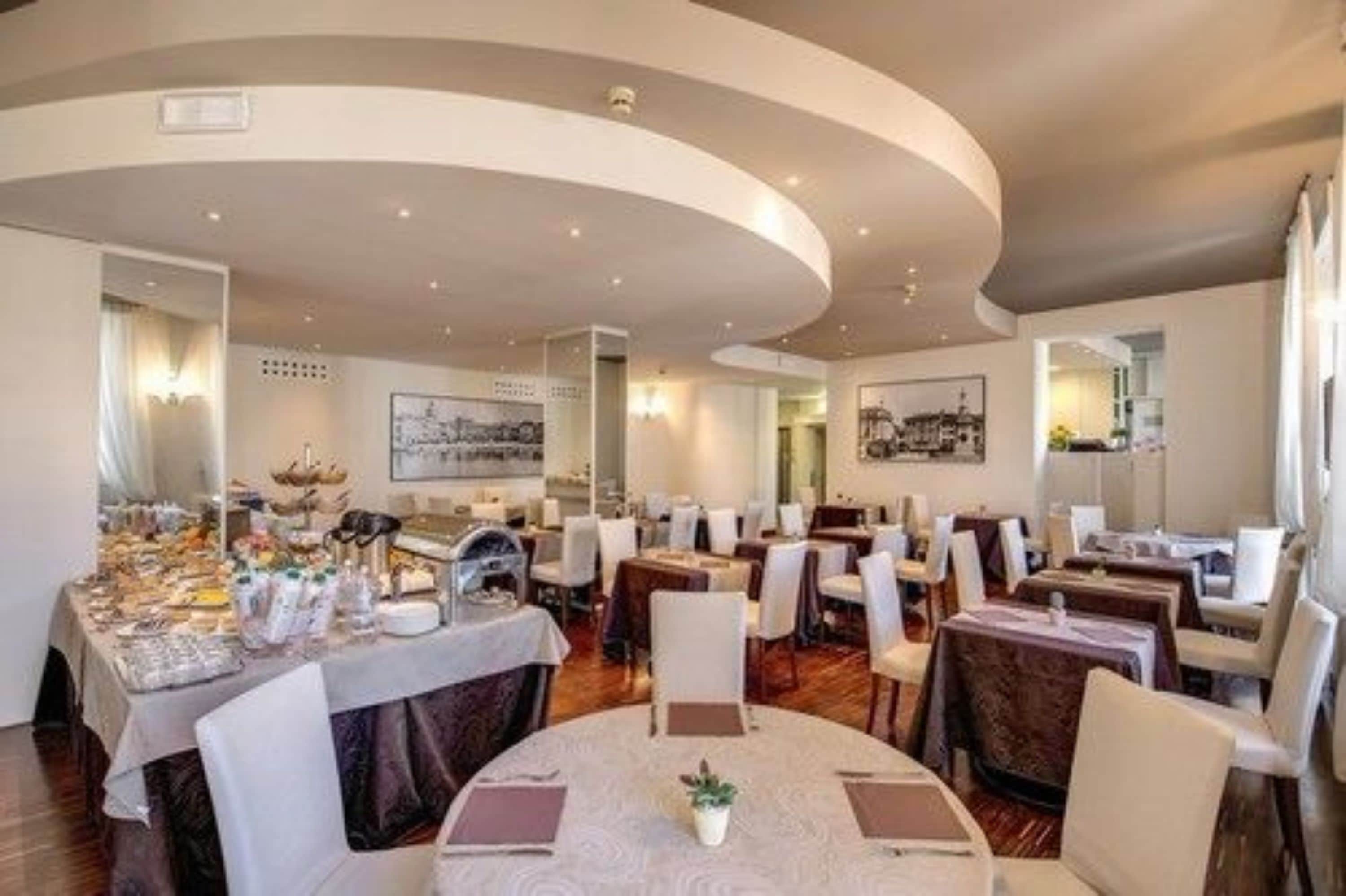 A restaurant with round tables and chairs, a curved ceiling, and framed artwork on the walls.