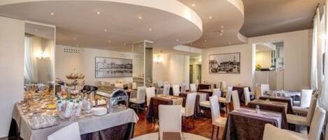A restaurant with round tables and chairs, a curved ceiling, and framed artwork on the walls.