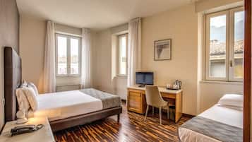 Een hotelkamer met twee bedden, een bureau, een stoel, een televisie en een raam met gordijnen.
