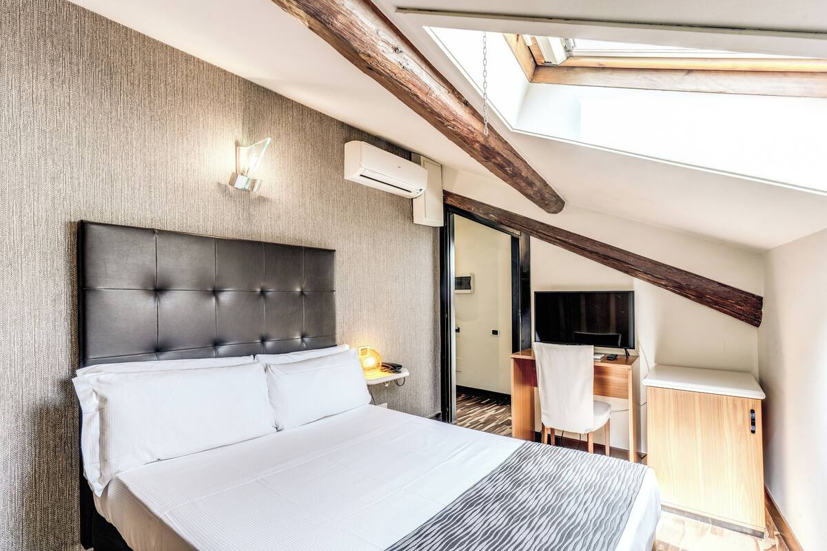Una habitación de hotel con una cama grande, un escritorio, una silla y un televisor.