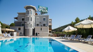 Um hotel com piscina, cadeiras de descanso e guarda-sóis.
