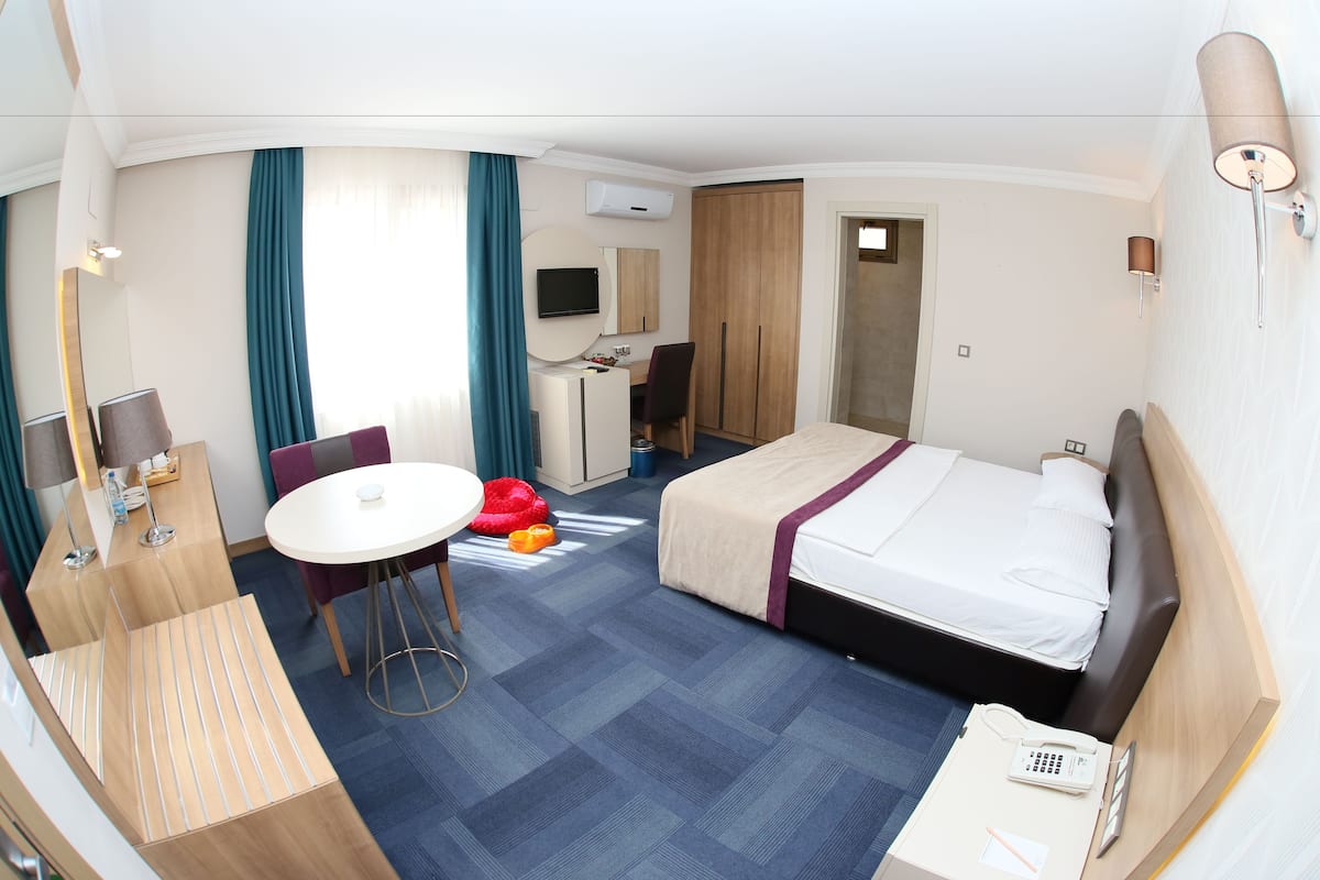 Habitación de hotel con cama, escritorio, silla y una pequeña mesa.