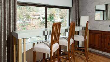 A kitchen with wooden chairs, a white countertop, and a window with curtains.