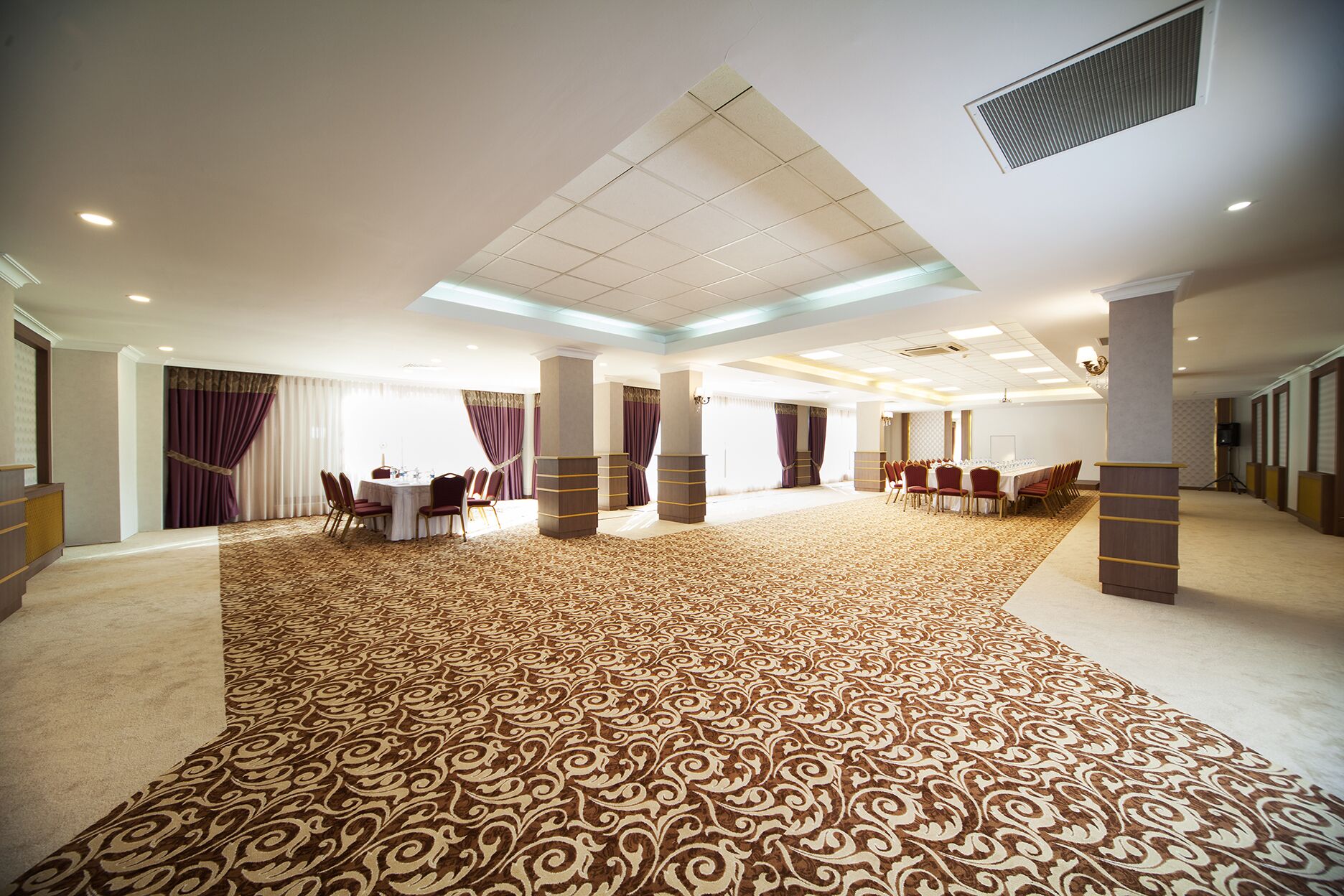Una amplia sala de conferencias con alfombra estampada, varias mesas y sillas.