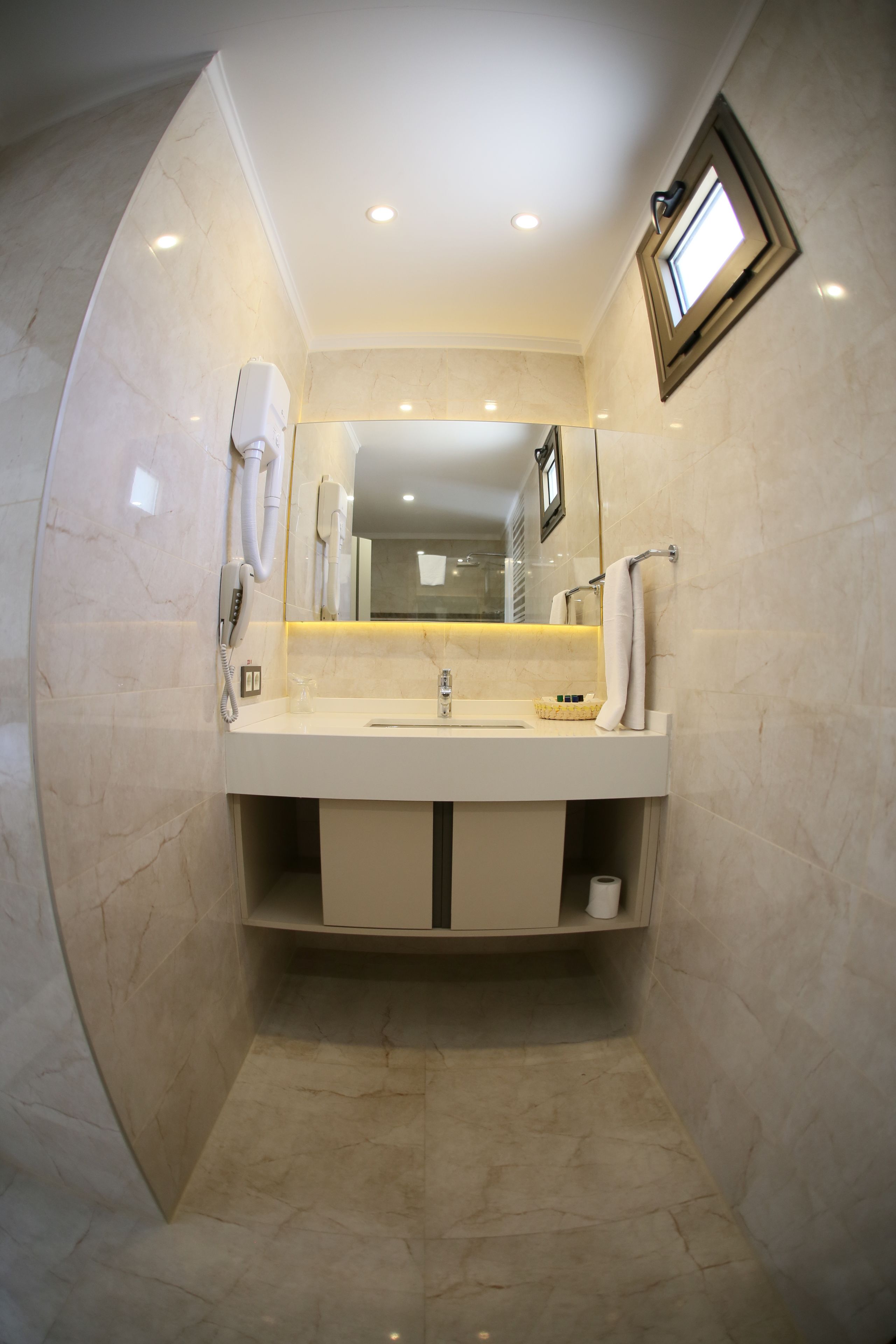 A modern bathroom with a marble floor, a sink with a mirror above it, a towel rack, and a small window.