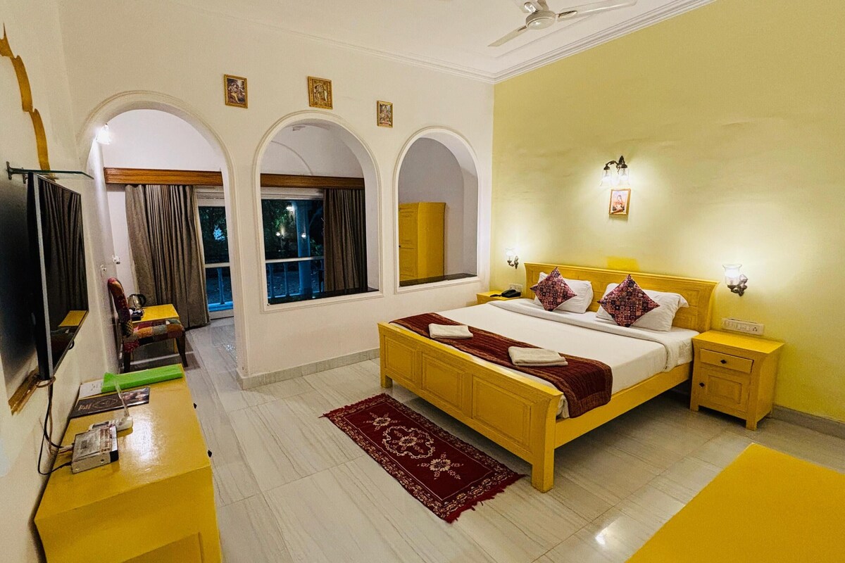 A bedroom with a bed, bedside tables, a TV, and a window.
