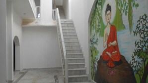 A staircase in a building with a mural on the wall depicting a figure in red. - Hotel Isabel Palace (Rajnagar)