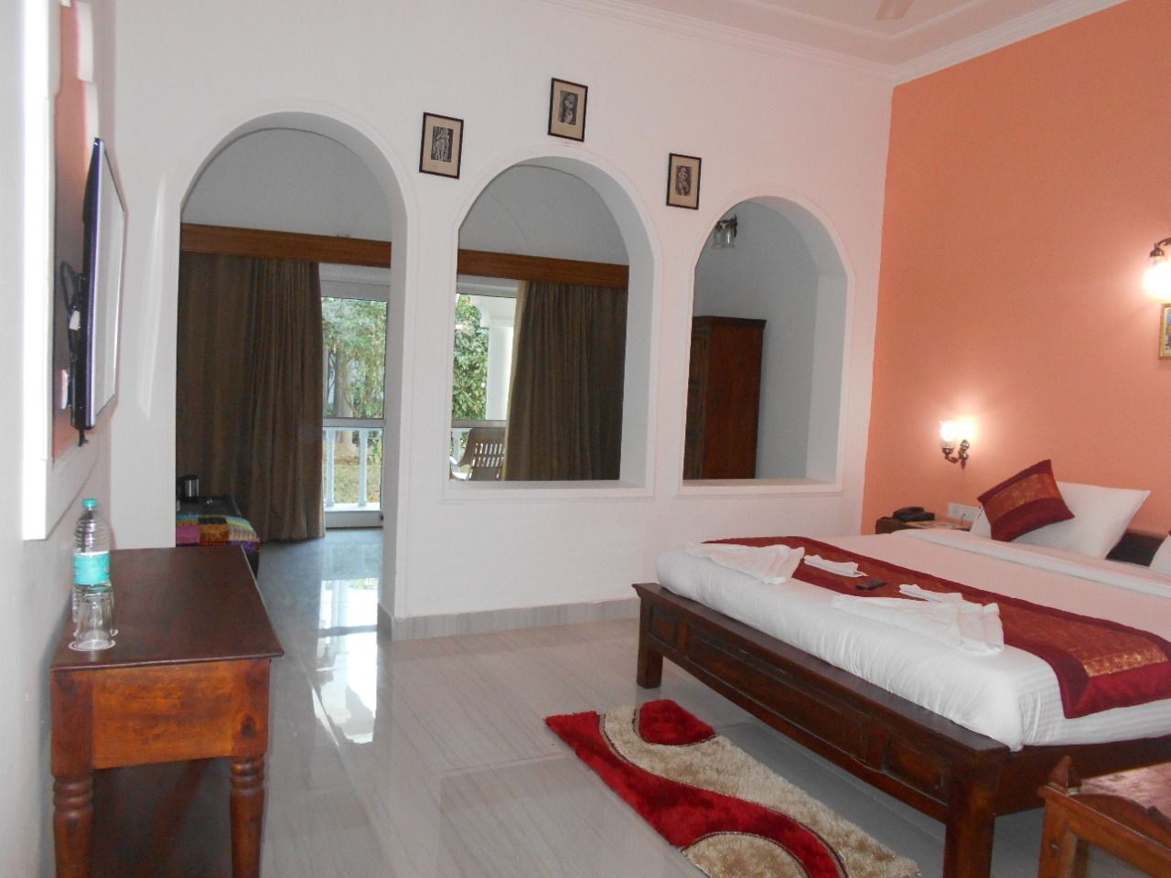 Una habitación de hotel con cama, escritorio y vista a través de un arco.
