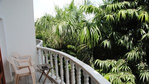 A balcony with a white balustrade, two plastic chairs, and a small table. - Hotel Isabel Palace (Rajnagar)