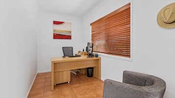 A small office space with a desk, chair, and a window with blinds.