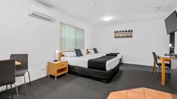 A hotel room with a bed, bedside table, lamp, chair, desk, and a television.