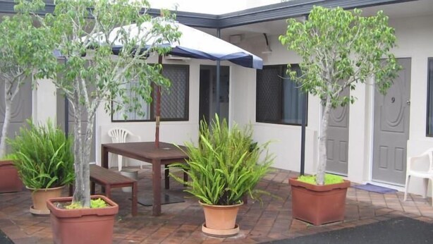 A patio area with a table and chairs, surrounded by potted plants and a covered seating area. - River Park Motor Inn (Casino)