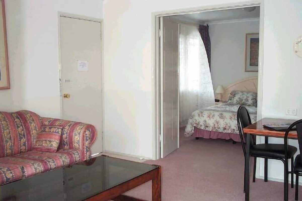 A room with a sofa, a table, and a bed.