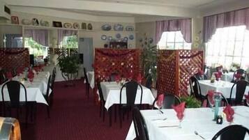 Un restaurante con varias mesas y sillas, una alfombra roja y elementos decorativos en las paredes.