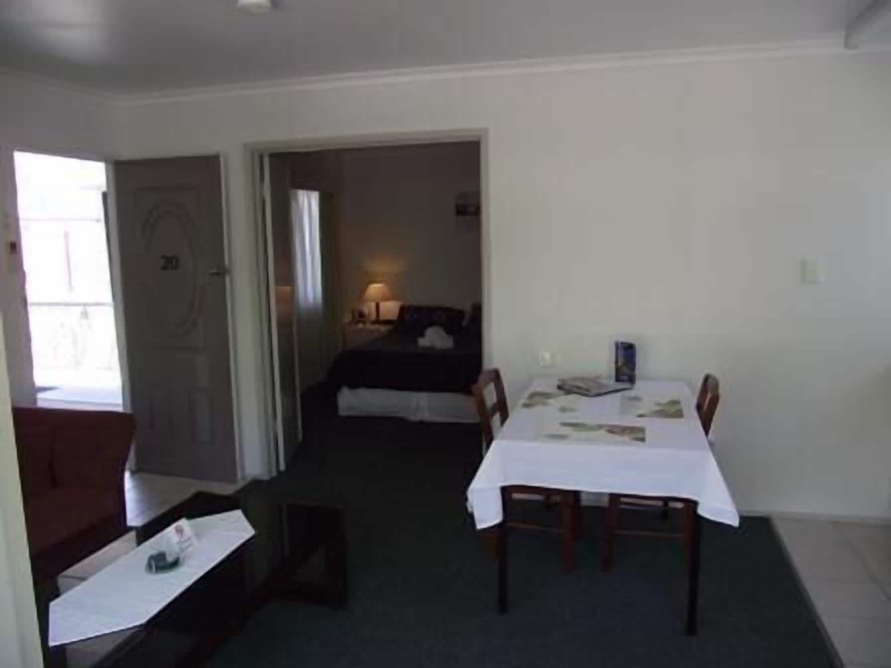 Una habitación de hotel con una cama, una mesa de comedor con sillas y un escritorio pequeño con una silla.