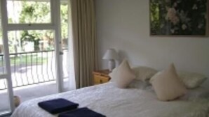 A bedroom with a bed, pillows, a nightstand, a lamp, and a painting on the wall. - River Park Motor Inn (Casino)