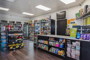 A well-lit store with shelves stocked with various products including snacks, beverages, and household items.