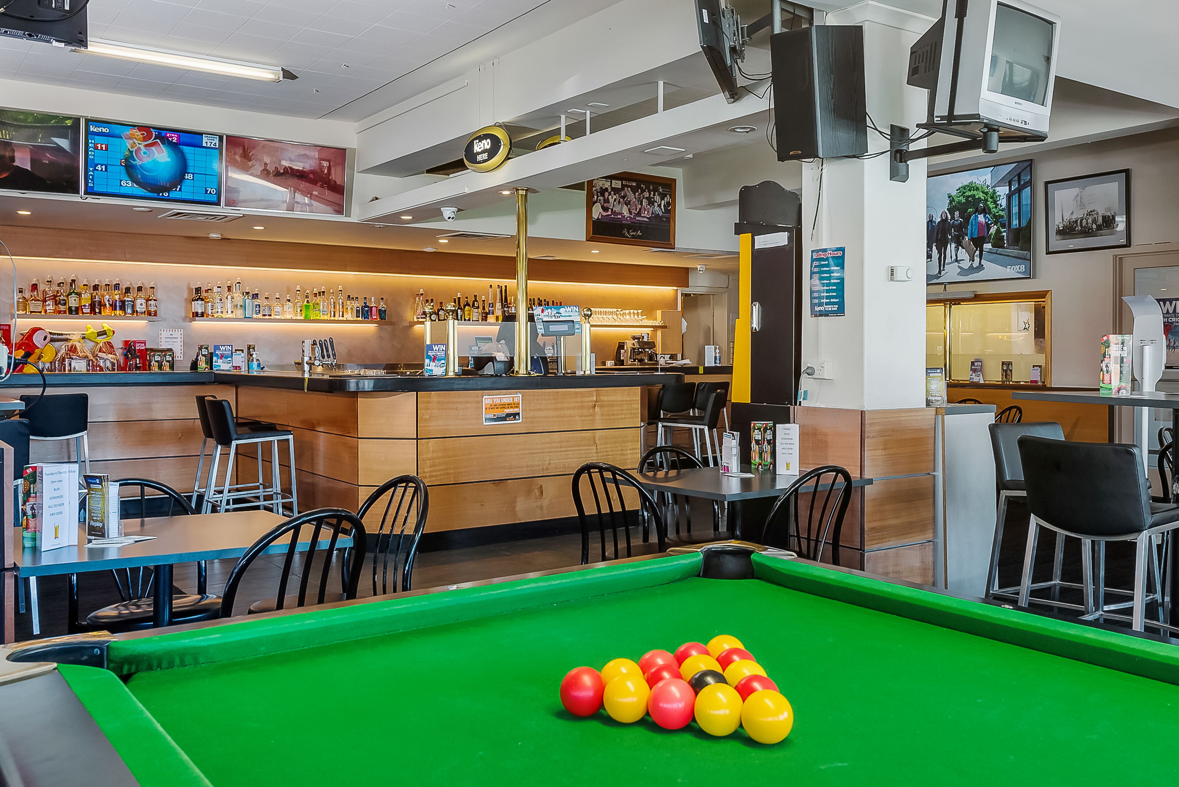 A billiards table with balls, a bar area with bottles, and seating.