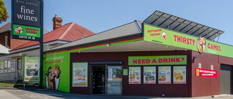 A building with a green and red exterior, featuring a 'Thirsty Camel' sign and a 'Bottleshop Parking' sign.