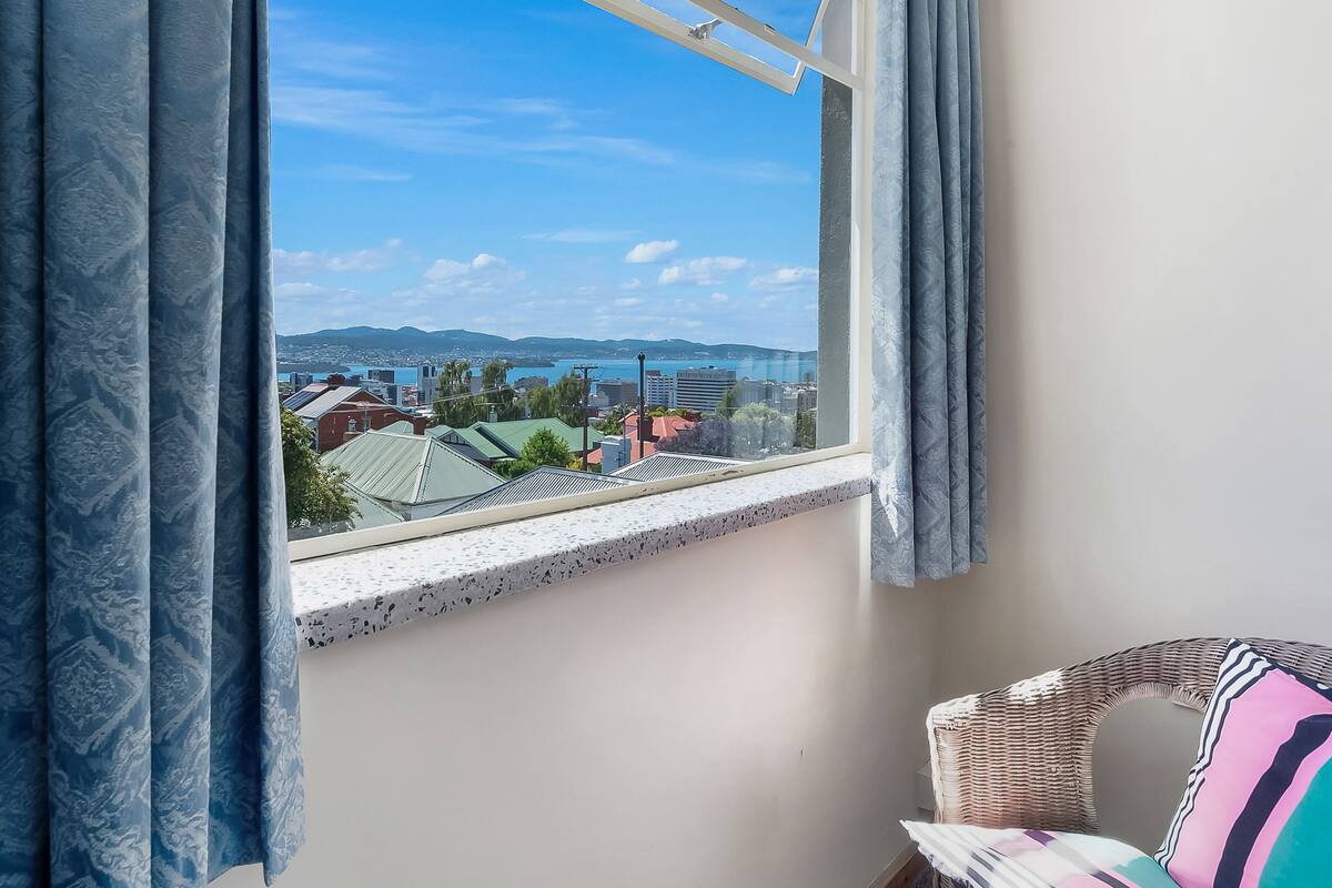 Ein Zimmer mit Blick auf eine Stadtlandschaft durch ein Fenster mit Vorhängen.