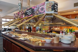 A buffet area with a variety of food items and a decorative sign above the counter.