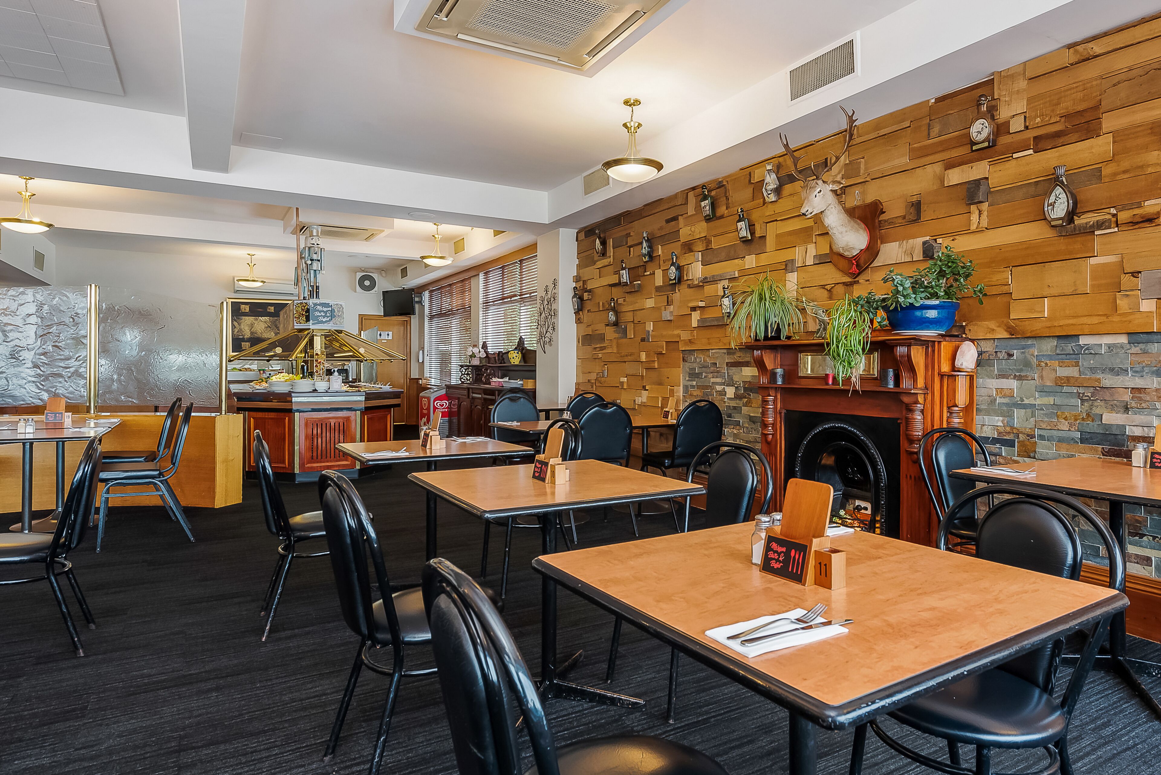 A restaurant with wooden wall decor, a fireplace, and multiple tables and chairs.
