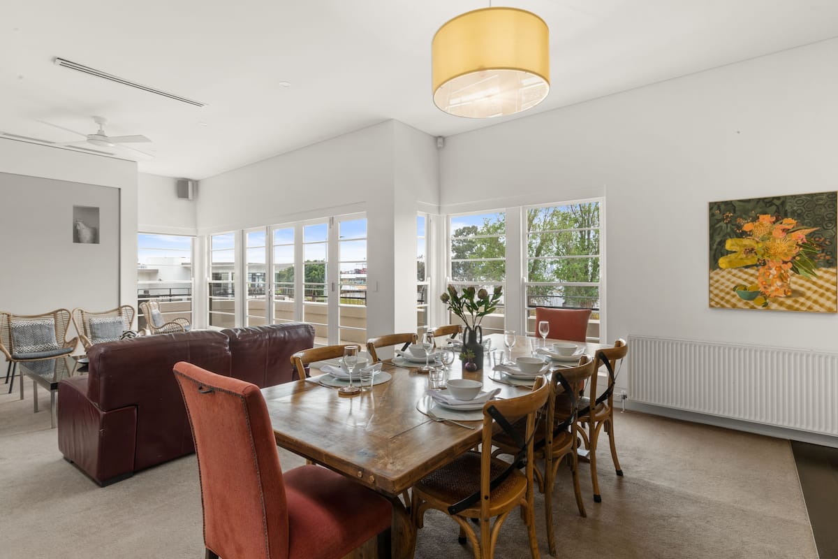 Un coin repas avec une table en bois dressée pour six personnes, entourée de chaises en bois.