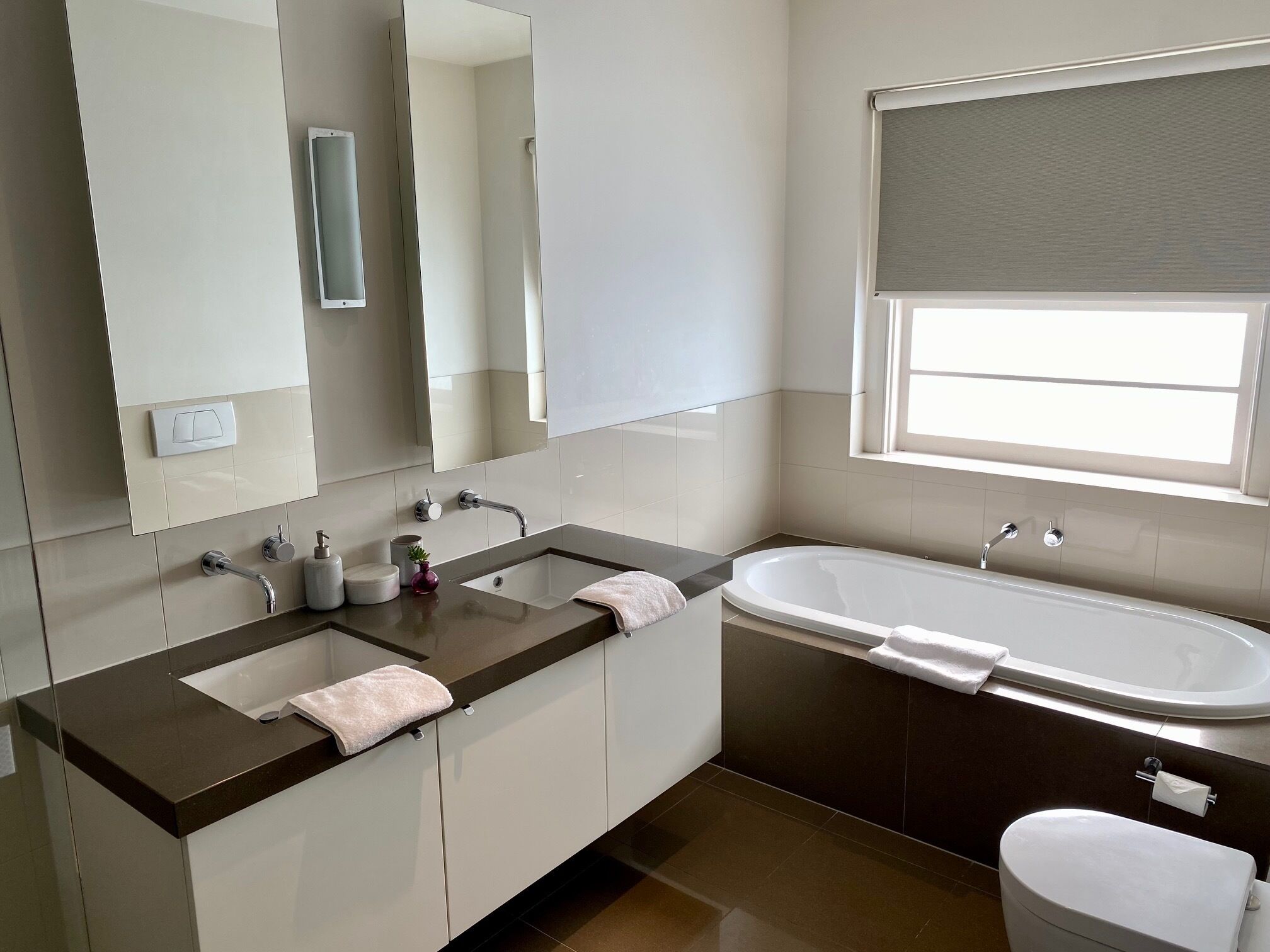 Une salle de bain moderne avec un meuble-lavabo à deux vasques, une baignoire et des toilettes.