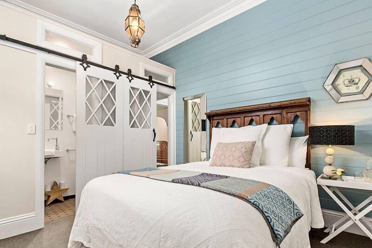 Une chambre à coucher comprenant un lit, une table de chevet, une commode et un placard avec une porte coulissante.