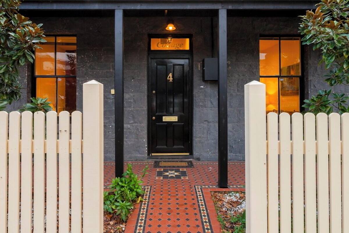 Une porte noire avec une enseigne au-dessus indiquant : « The Cottage ».
