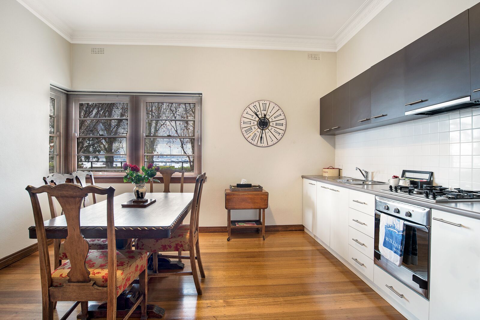 Una cocina moderna con armarios blancos, una estufa de acero inoxidable y un reloj en la pared.