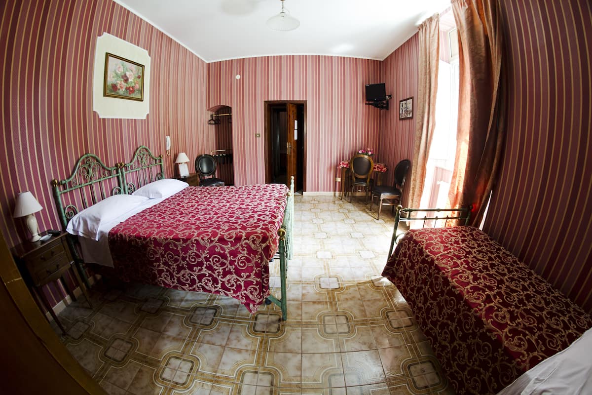 Una habitación con dos camas, un escritorio, una silla, una lámpara y un cuadro en la pared.