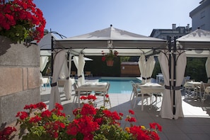 Una piscina al aire libre, sombrillas, sillones reclinables de piscina
