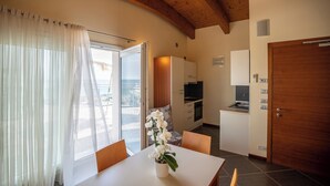 A compact kitchen with a dining area, a wooden ceiling, and a view through the window. - Hotel Coppe (Jesolo)